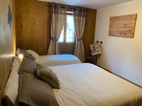 una camera da letto con due letti e una finestra di Appartamento Le Cigamole a Valfurva