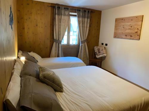 una camera da letto con due letti e una finestra di Appartamento Le Cigamole a Valfurva