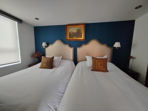 two beds in a room with blue walls at Ana Frank Boutique Hotel in Lima