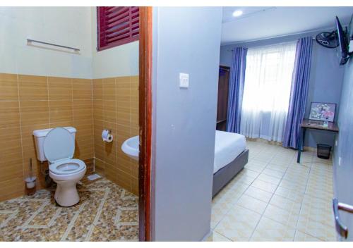 a bathroom with a toilet and a bed and a tub at The VIP Luxury CBD in Kisumu