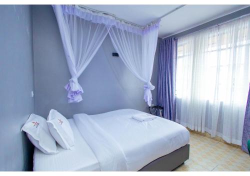 a bedroom with a white bed and a window at The VIP Luxury CBD in Kisumu