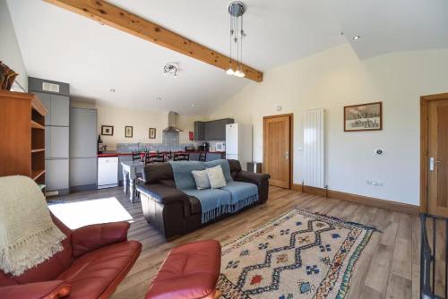 a living room with a couch and a kitchen at Amber Cabin in Ashover