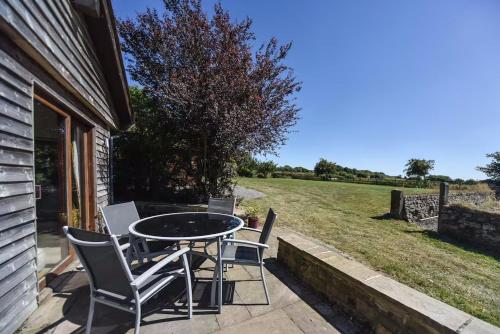 a patio with a table and chairs and a field at Amber Cabin in Ashover