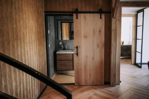a hallway with a door to a bathroom with a sink at Luxe buitenhuis 10 pers met jacuzzi en vrij uitzicht in Rheeze
