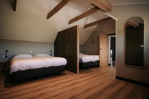 two beds in a room with wooden floors at Luxe buitenhuis 10 pers met jacuzzi en vrij uitzicht in Rheeze