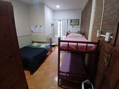 a small room with two beds and a table at El Guembe Hostel House in Puerto Iguazú