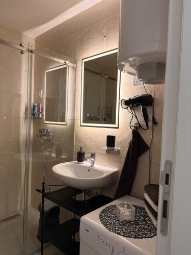 a small bathroom with a sink and a mirror at Fantasia apartmani - Tesla palace in Kragujevac