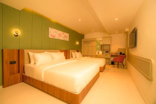 een slaapkamer met een groot bed en een groene muur bij Hotel Harriet in Rāmeswaram