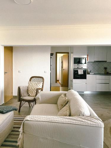 a living room with a white couch and a kitchen at Cantinho de Belmonte in Belmonte