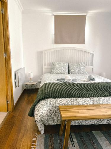 a white bedroom with a large bed and a table at Cantinho de Belmonte in Belmonte