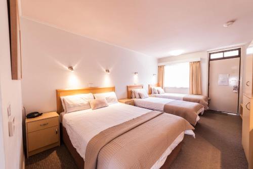a hotel room with three beds and a window at Eastern Sands City Centre in Geelong