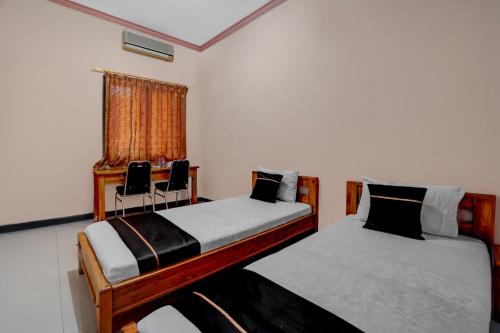 two beds in a room with a window at OYO 94899 Homestay Syariah Near UPN in Medokanayu