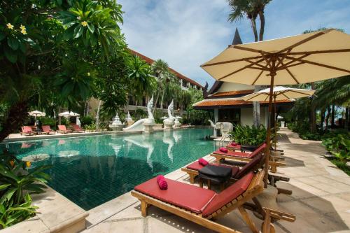 a swimming pool with lounge chairs and an umbrella at Dor-Shada Resort By The Sea in Na Jomtien