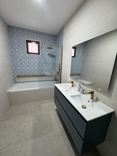 a bathroom with a sink and a tub and a mirror at Casa da Parreira in Loulé