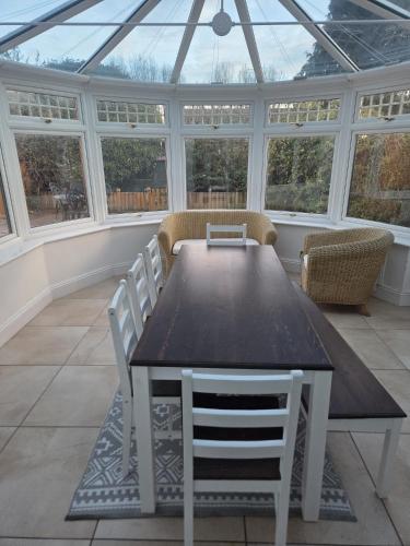 a conservatory with a table and chairs and windows at Comfy Home- Coley Park in Reading