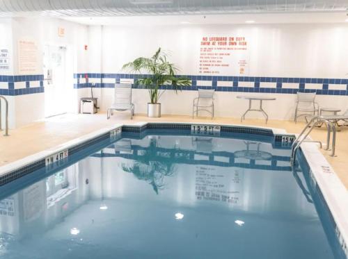 a swimming pool with chairs and tables in a building at Holiday Inn Express Hotel & Suites Warwick-Providence Airport by IHG in Warwick
