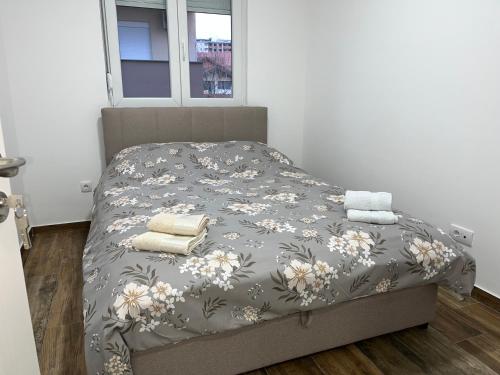 a bed with a gray comforter with towels on it at Mimura 3 in Belgrade