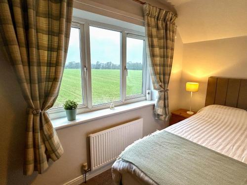een slaapkamer met een bed en een raam met een groen veld bij Scamnel in Norton Bridge