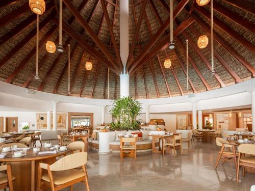 蓬塔卡纳Zel Punta Cana - All Suites的一间带桌椅和大型天花板的餐厅