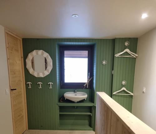 een groene badkamer met een wastafel en een raam bij CHALETS JEANNE & ARNOL à Allemond - Grand Domaine Alpe d'Huez in Allemont