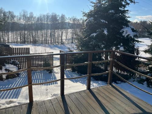 een houten vlonderpad in de sneeuw met een kerstboom bij The Nest - Sauna and Hot Tub in Rynoltice