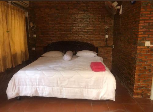 a bedroom with a white bed in a brick wall at Kampot Riverside GuessHouse in Phumĭ Ândong Pring