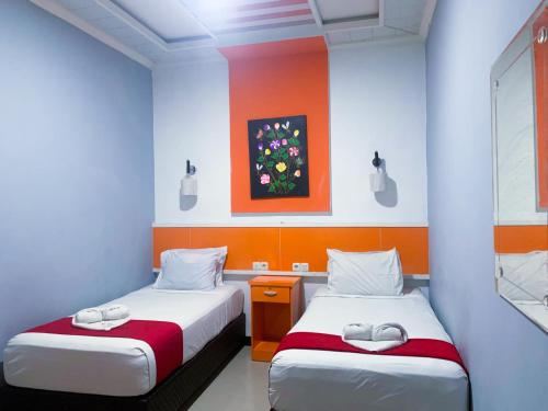 two beds in a room with orange and blue walls at Hotel Grand illa palopo in Palopo