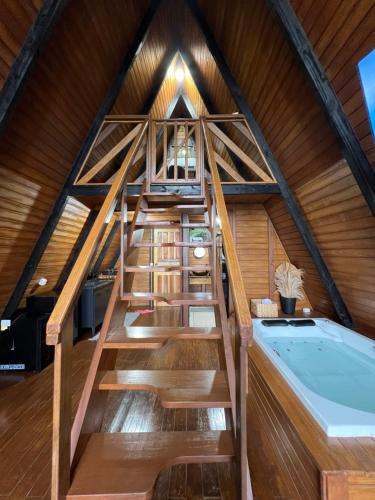an attic bathroom with a staircase and a tub at Chalé das pedras in Massaranduba
