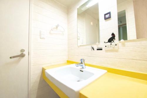 a white bathroom with a sink and a mirror at Yume House in Furano