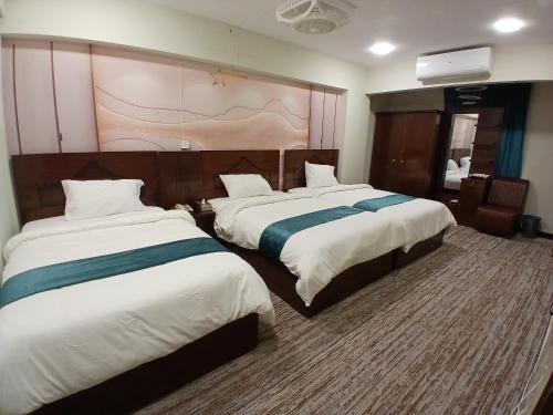 a hotel room with two beds and avertisement at Prime Star Hotel in Karachi