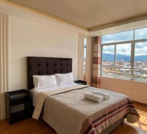 a bedroom with a large bed with a large window at Hotel Killasumaq in Cajamarca