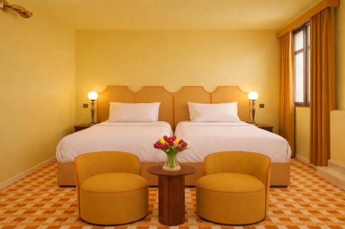 ein Hotelzimmer mit zwei Betten und zwei Stühlen in der Unterkunft Latroupe Hotel Le Berger in Brüssel