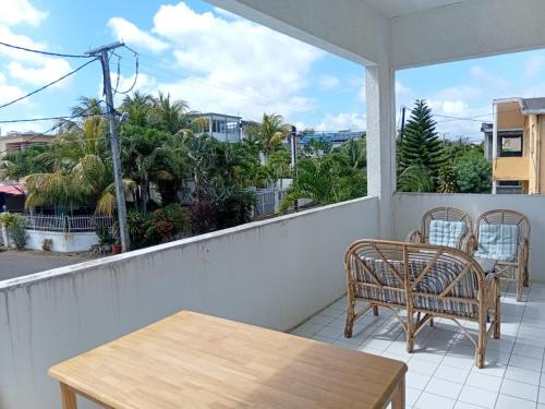 een veranda met 2 stoelen en een tafel op een balkon bij La Oursha Apartment in Pointe aux Biches
