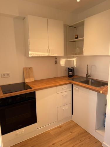 een keuken met witte kasten en een spoelbak bij Konstanz Lakeside Apartment in Reichenau