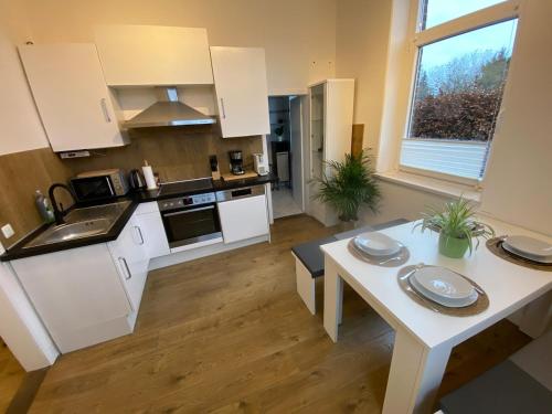 eine Küche mit weißen Schränken und einem Tisch mit Tellern darauf in der Unterkunft Studio Apartment nahe Lüneburg in Bienenbüttel