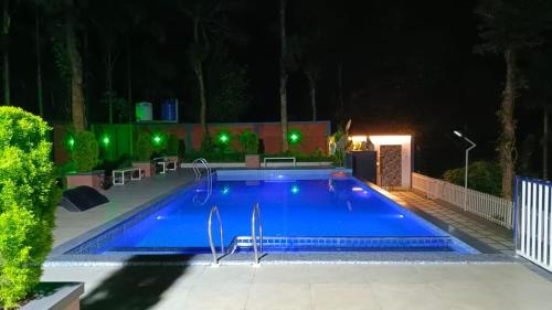 a swimming pool at night with green lights at Nellar Dream Resort in Meppādi