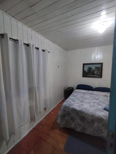 een slaapkamer met een bed en witte gordijnen erin bij Quarto Cama Casal in Gramado