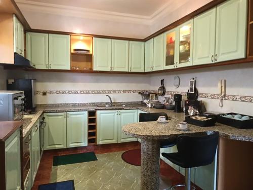 una cucina con armadi verdi e un tavolo con sedie di Villa stade Moulay Abdellah a Temara