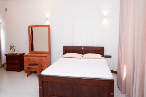 een slaapkamer met een bed, een ladekast en een spiegel bij Villa NU 380 in Galle