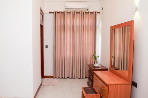 een woonkamer met een dressoir en een spiegel bij Villa NU 380 in Galle