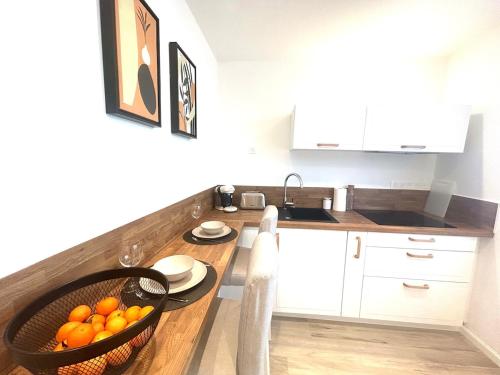 a kitchen with a table with a basket of oranges at Studio cosy refait à neuf - Parking privé in Lanester