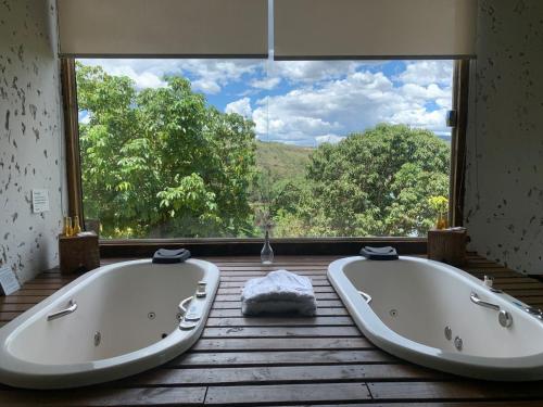 due vasche da bagno in una stanza con una grande finestra di Pousada Piratas do Barro Branco a Pedregulho
