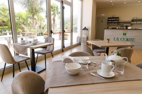 een restaurant met tafels, stoelen en ramen bij La Corte Park Hotel & Spa in Palma Campania