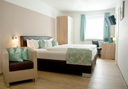 Habitación de hotel con cama y silla en Hotel Claro Garni, en Eitting