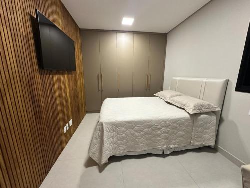 een slaapkamer met een bed en een flatscreen-tv bij Apartamento moderno no Horto in Ipatinga