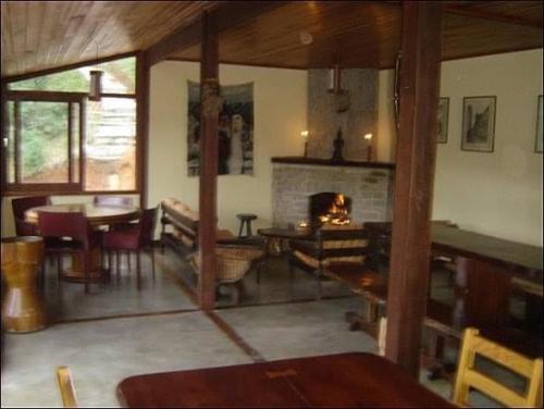 a living room with a table and a fireplace at Refugioecolodge in Nova Friburgo