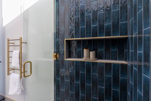 een badkamer met een blauwe betegelde muur met planken bij Trails End - Architectually designed retreat in Punakaiki