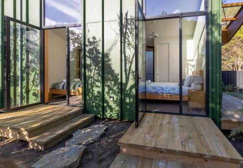 een glazen huis met een slaapkamer en een bed bij Trails End - Architectually designed retreat in Punakaiki