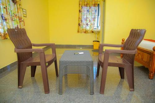 a room with two chairs and a table and a bed at JR Residency in Usilampatti