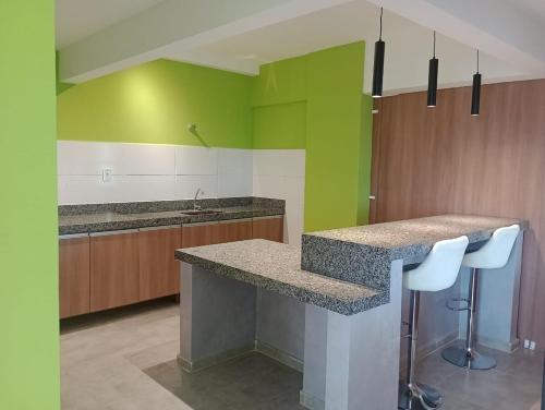 a kitchen with green walls and a counter with stools at Studio Sereno in Barbacena